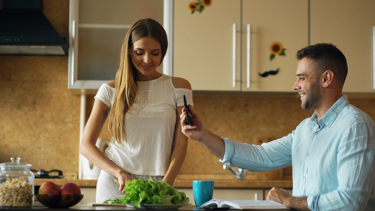 Attractive couple in the kitchen early morning cooking and have online video chat using tablet computer camera at home