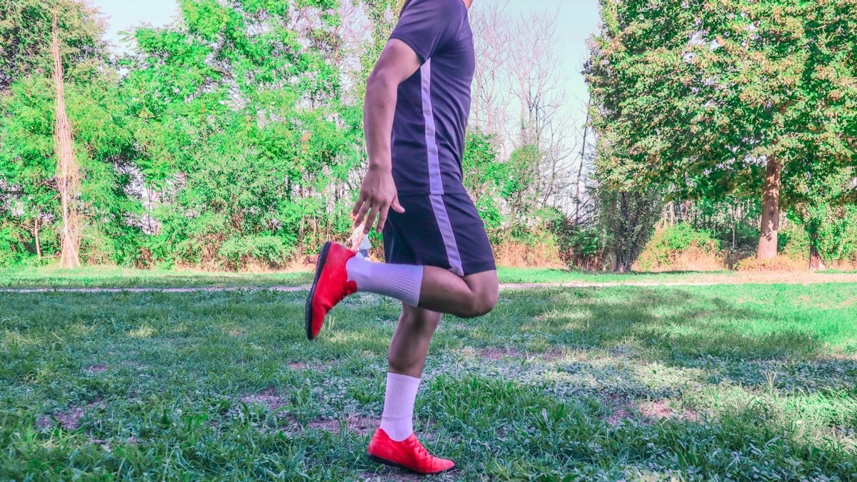 a person in a black dress and red shoes running on grass
